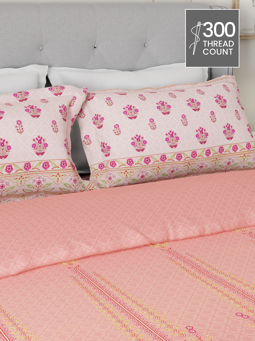 Pink floral bedspread with matching pillows on a bed with a gray headboard, featuring a 300 thread count label.
