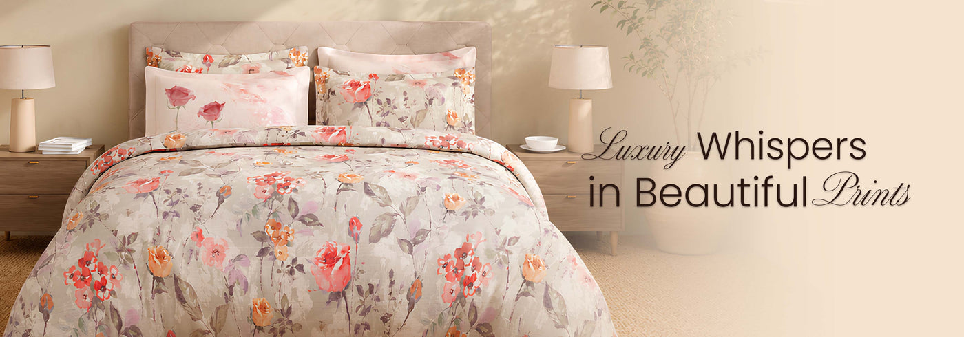 Floral bedding set on a bed with lamps and text 'Luxury Whispers in Beautiful Prints' on a beige background.