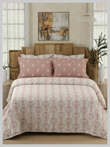 Bed with pink and white patterned bedding in a bedroom setting.