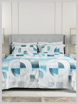 Bed with blue and white geometric patterned bedding in a room with a gray headboard.