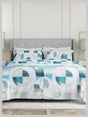 Bed with blue and white geometric patterned bedding in a room with a gray headboard.